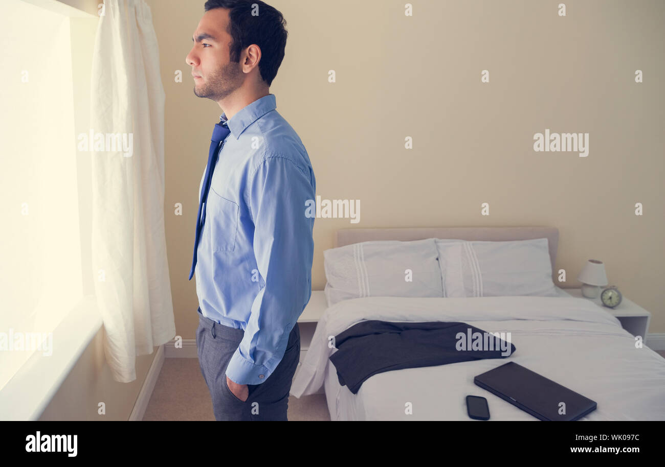 Frowning man standing looking out the window Stock Photo