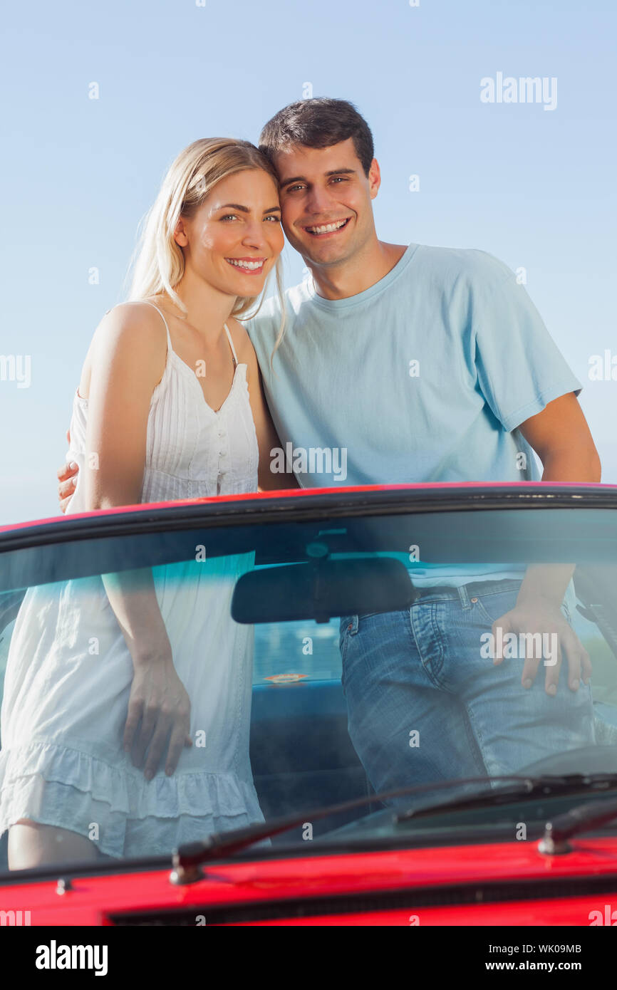 Smiling couple standing in red cabriolet posing Stock Photo