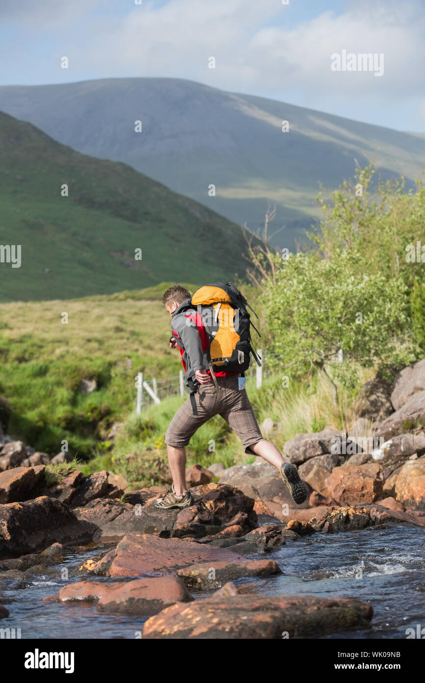 Man crossing a river on a hike Stock Photo