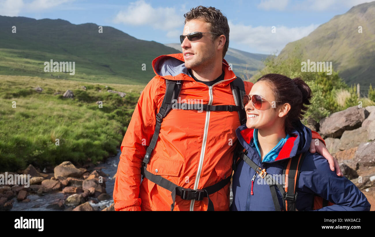 Couple wearing rain jackets and sunglasses admiring the countryside Stock Photo
