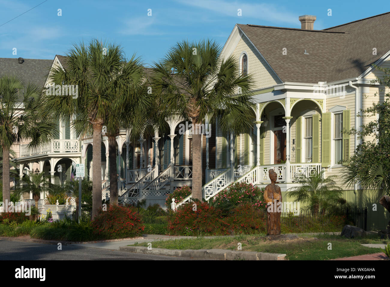 In one sense, this is a photograph of a lovely row of houses in Galveston, Texas. But look closely in the figure in the foreground. In 2008, ferocious Hurricane Ike and its surge of high salt water killed an estimated 40,000 trees. But Galveston Island Tree Conservancy member Donna Leibbert found chain saw sculptors to create art from the dead trees in the historic district. This is one of them Stock Photo