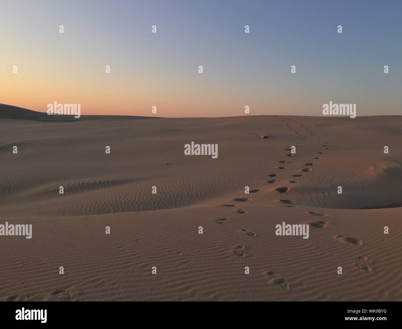 Footprints On Sand Dunes Against Clear Sky During Sunset At Port Stephens Stock Photo