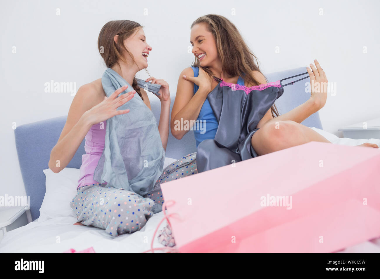 Teen girls sitting on bed after shopping Stock Photo