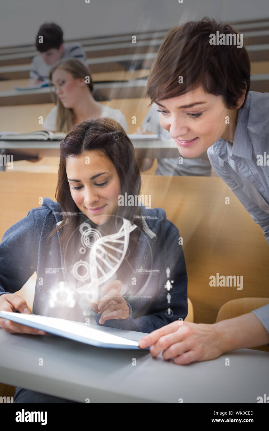 Student sitting while teacher is explaining on tablet pc in lecture hall Stock Photo