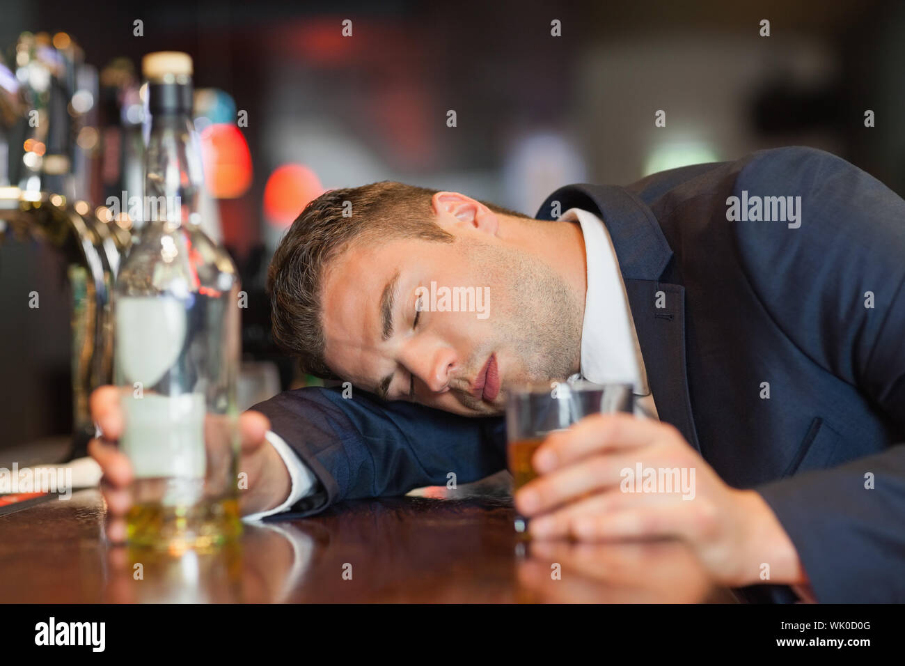 Unconscious businessman holding whiskey glass lying on a counter Stock ...