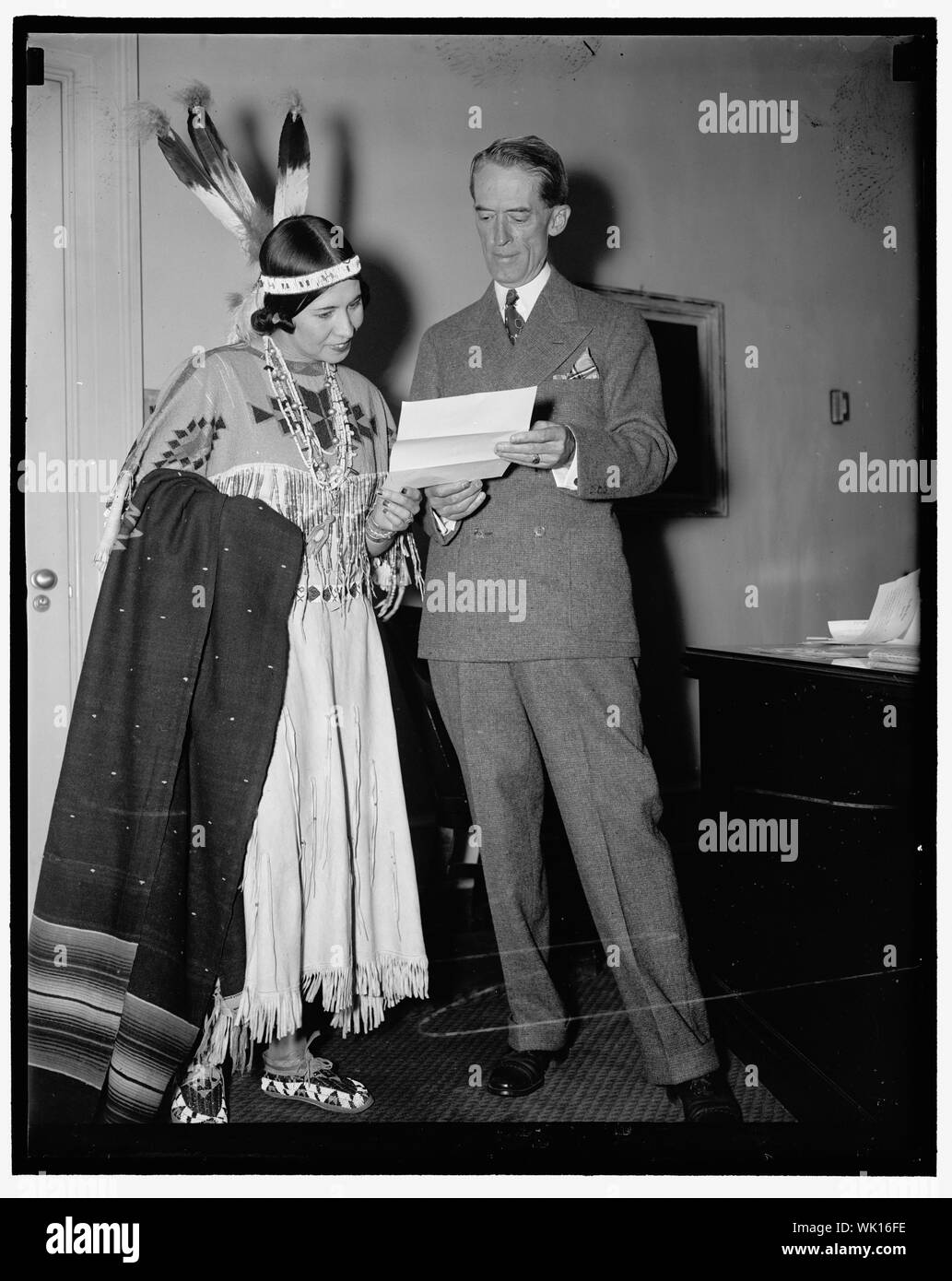 Indian Princess invites President Grand Council Washington D.C. June 28. Dressed in full regalia, Princess White Deer, extended an invitation to President Roosevelt at the White House today to attend the Six Nations Iroquis Grand Indian Council July 5 at St. Regis Reservation. The Princess; who is shown with Presidential Secretary Marvin H. McIntyre said the Indian powwow will be the first time Iroquis Indians have held their council since pre-revolutionary days. 6/28/37 Stock Photo