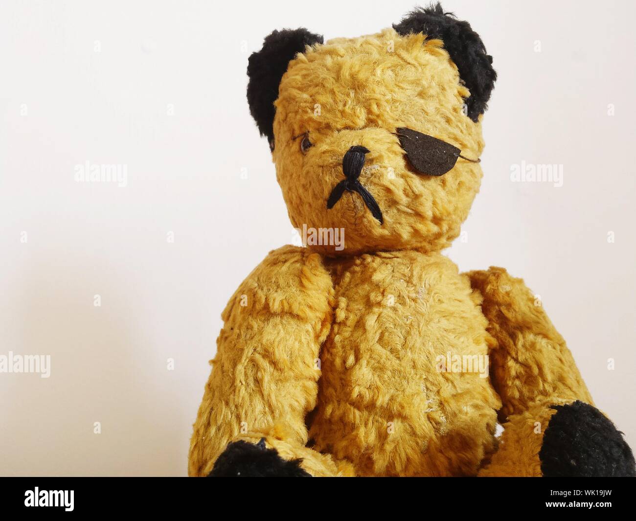 Close-up Of Teddy Bear Wearing Costume Eye Patch Against Wall Stock Photo