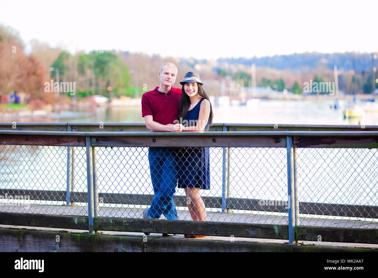 Young interracial couple standing together on wooden pier over lake Stock Photo