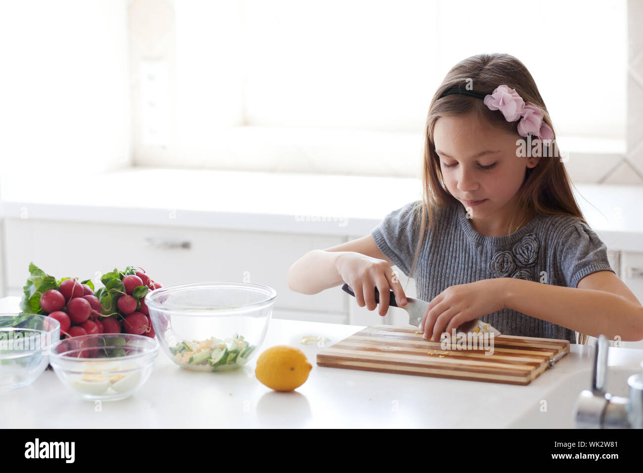 7 - 8 years old girl cooking in the white modern kitchen Stock Photo