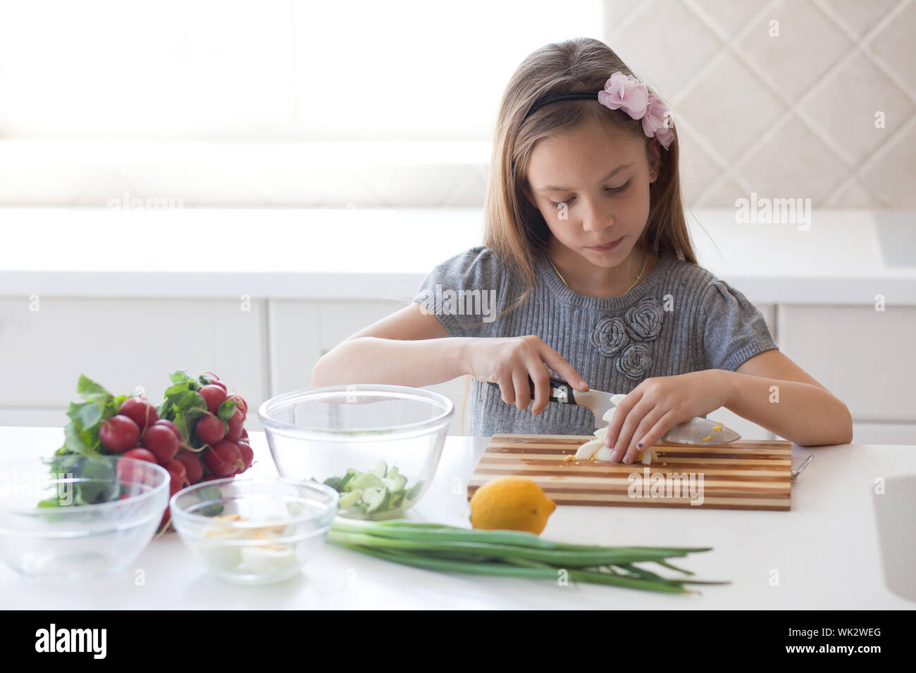 7 - 8 years old girl cooking in the white modern kitchen Stock Photo