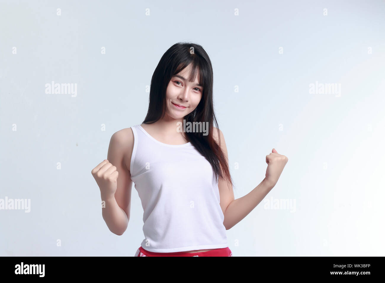 Portrait Of Woman Clenching Fist Against White Background Stock Photo