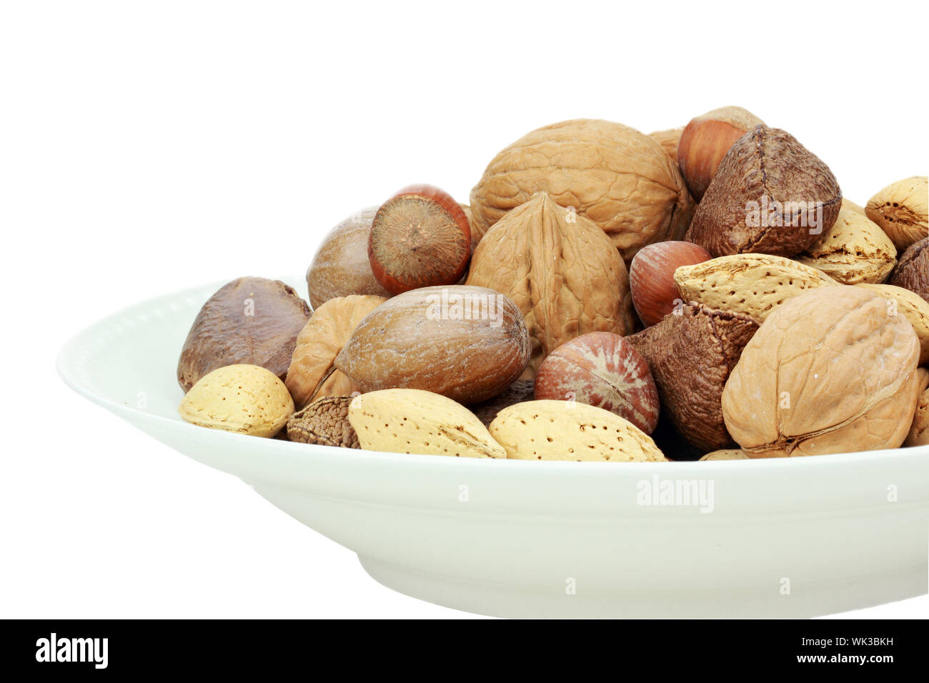 A variety of whole mixed nuts in the shell against a white background