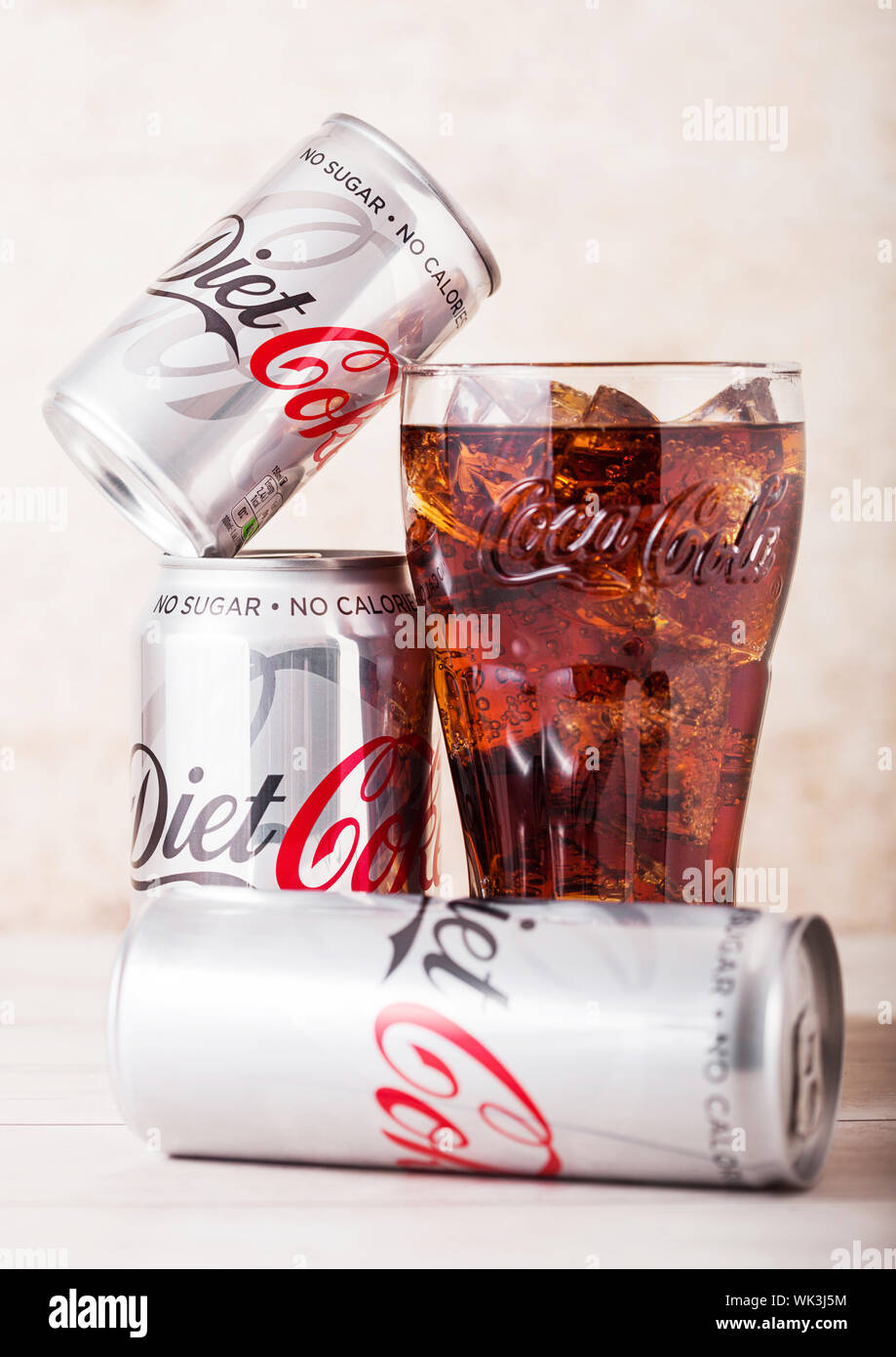 LONDON, UK - AUGUST 03, 2018: Aluminium tins and original glass of Diet Coke Coca Cola soft drink on wood. Most popular drink in the world. Stock Photo