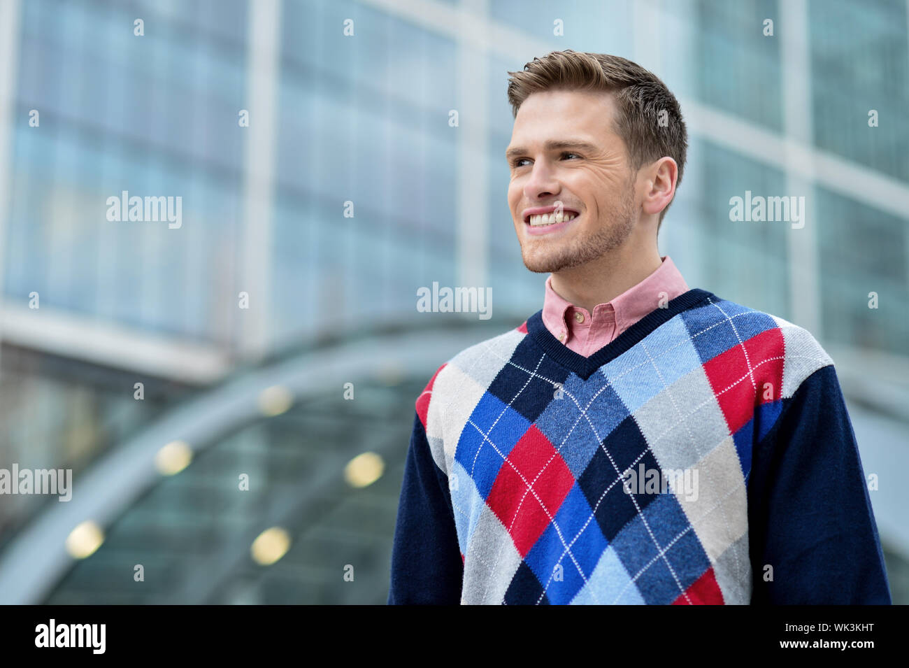 Smiling young man standing in front of office building Stock Photo - Alamy