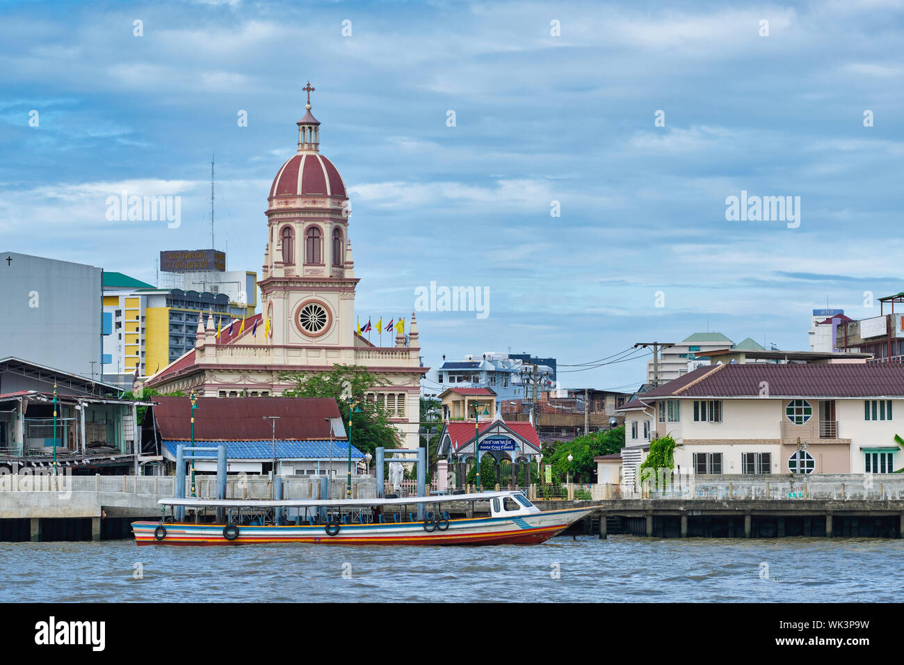 Portuguese-built Santa Cruz Church in Thonburi, Bangkok, Thailand, a river express boat in front; seen from the opposite bank of the Chao Phraya River Stock Photo