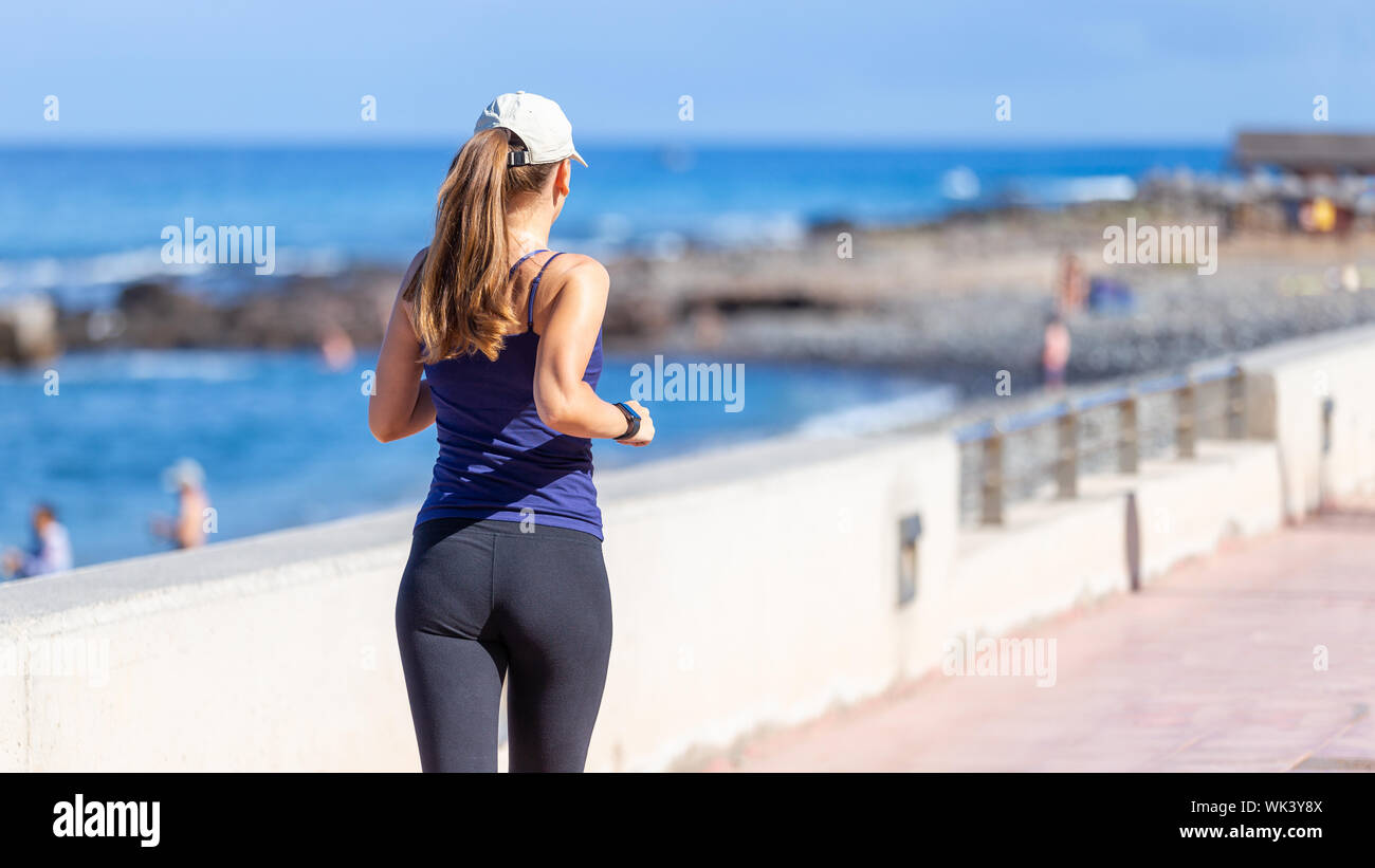Young sporty woman jogging near the ocean. Back view of running girl with copyspace Stock Photo