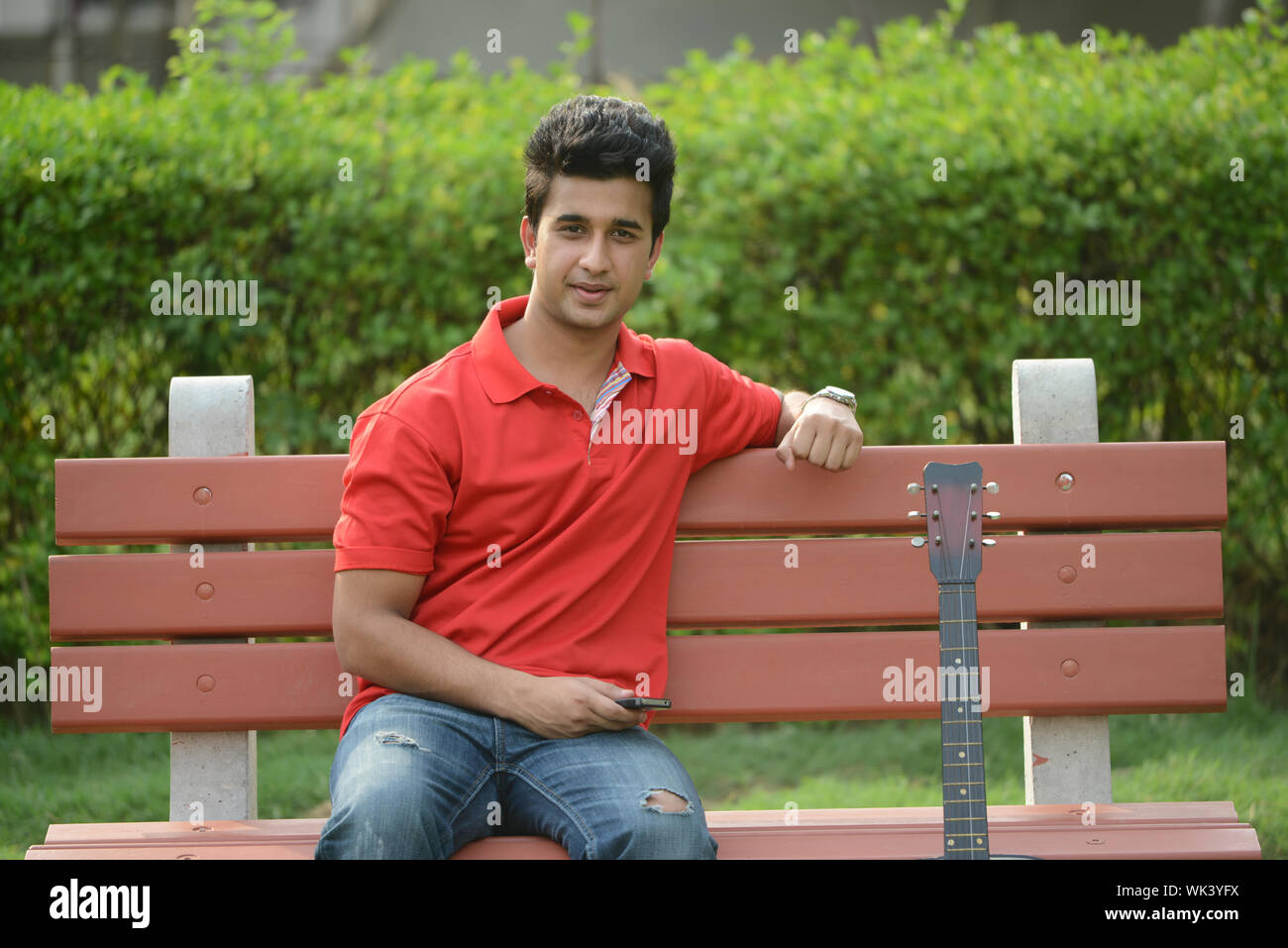 Young man sitting on a park bench in a lawn Stock Photo - Alamy