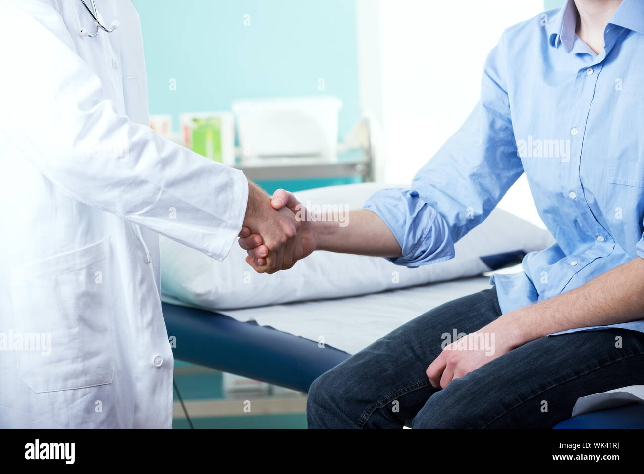 Doctor and patient handshake with medical equipment on the background ...