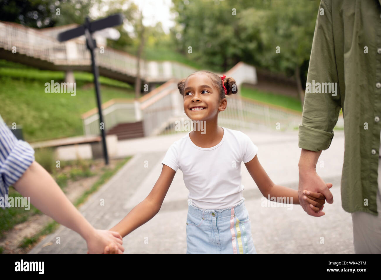Daughter making funny face while walking with parents Stock Photo