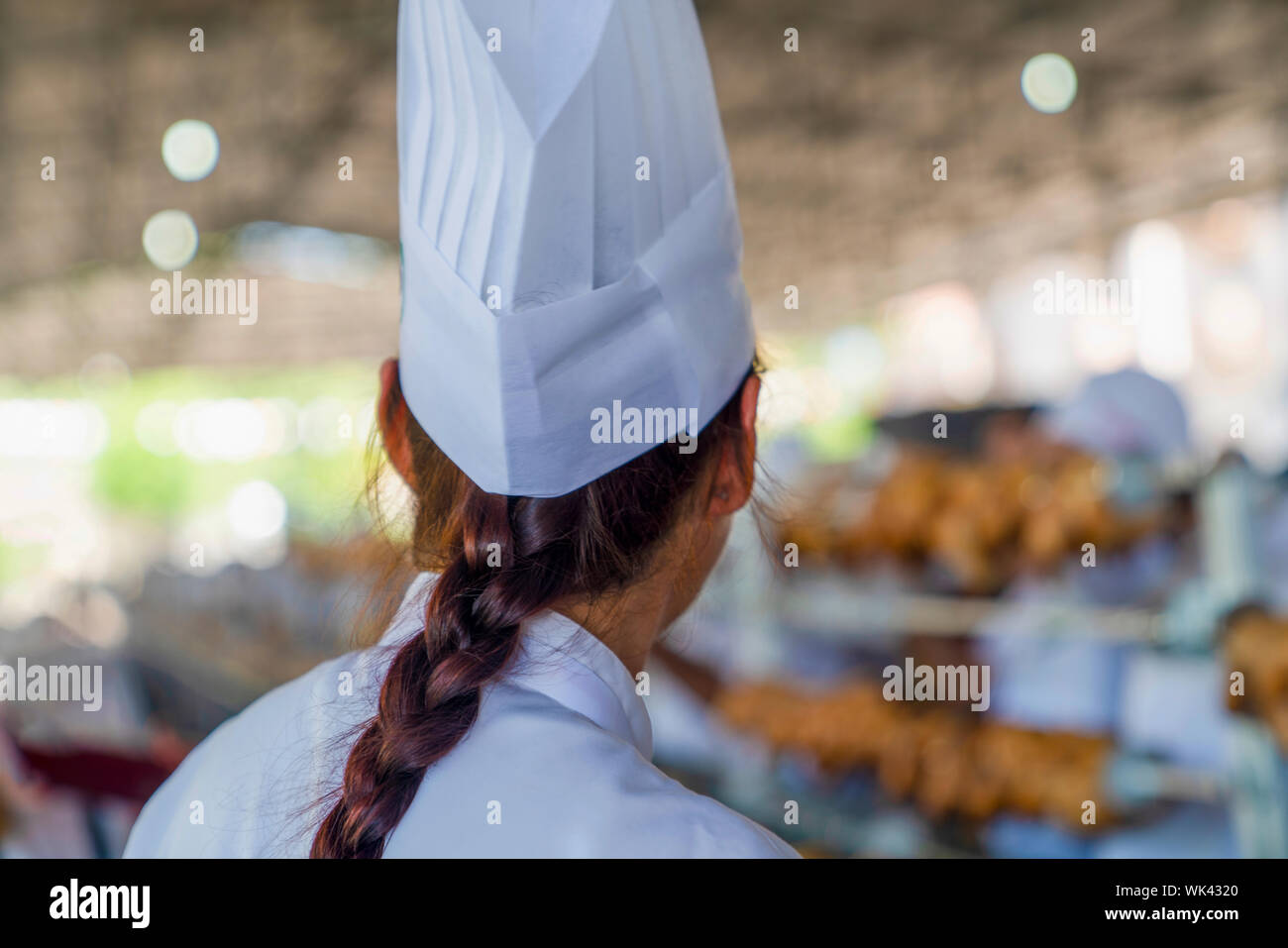 Many roasted chickens in a row in culinary and tourism Festival in Mengen, Bolu, Turkey. Rear (back) view of chef woman in festival. Stock Photo