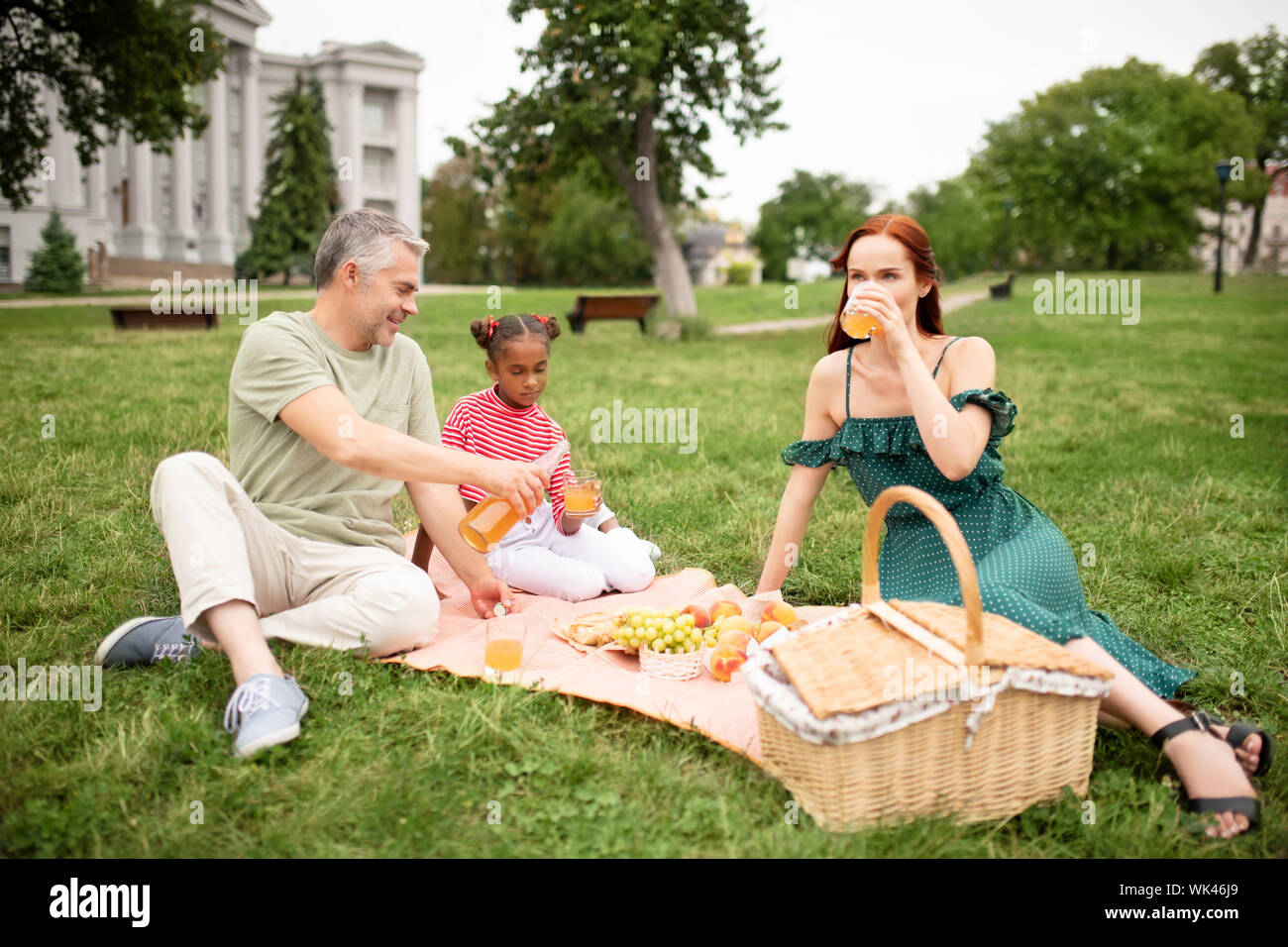 Daughter feeling joyful while having picnic with adoptive parents Stock Photo