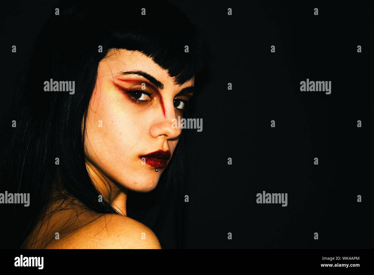 Side View Portrait Of Serious Young Woman With Eyeshadow Against Black Background Stock Photo