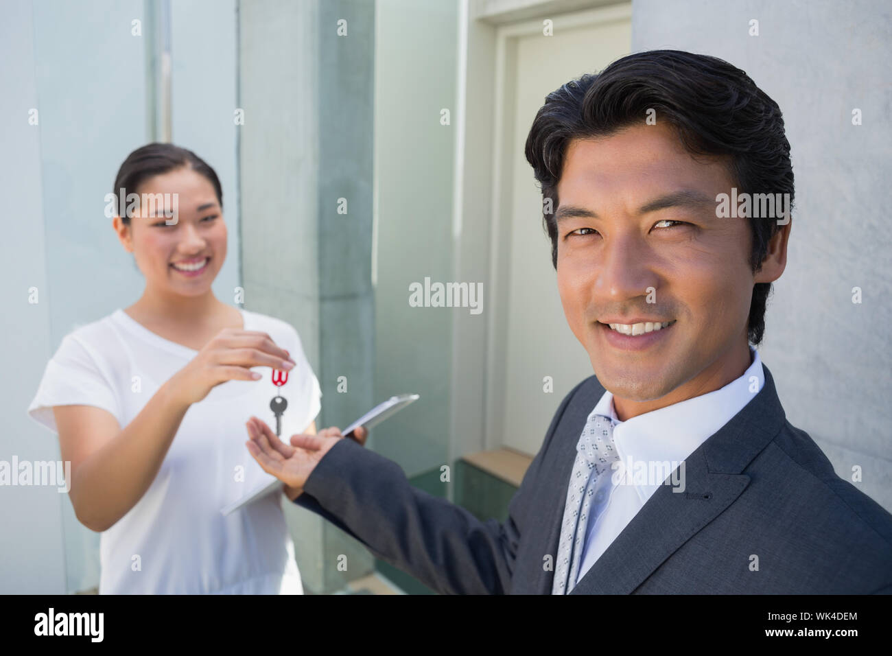 Estate agent giving house key to buyer outside a house Stock Photo - Alamy