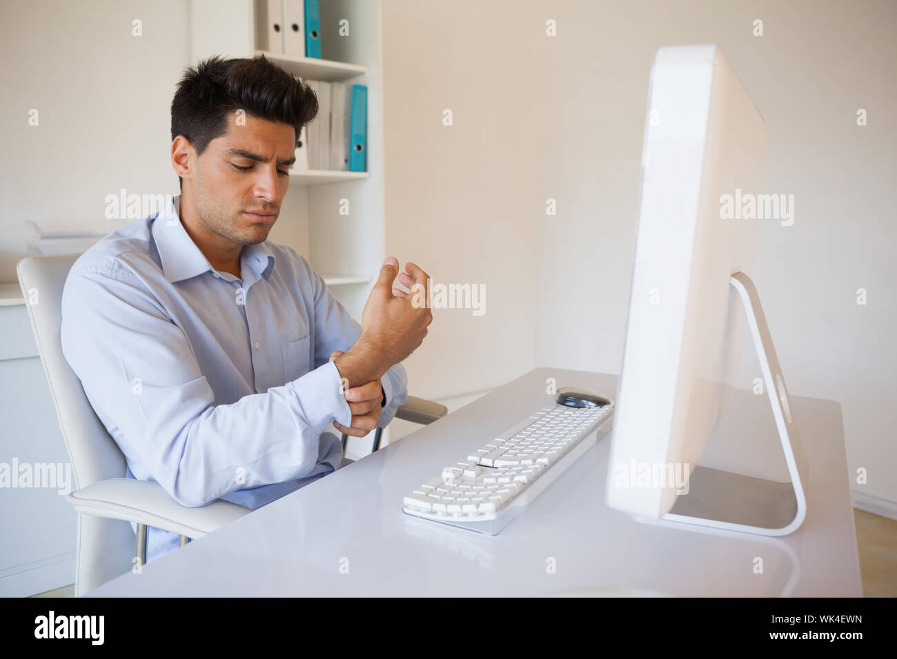 Casual businessman touching his sore wrist in his office Stock Photo