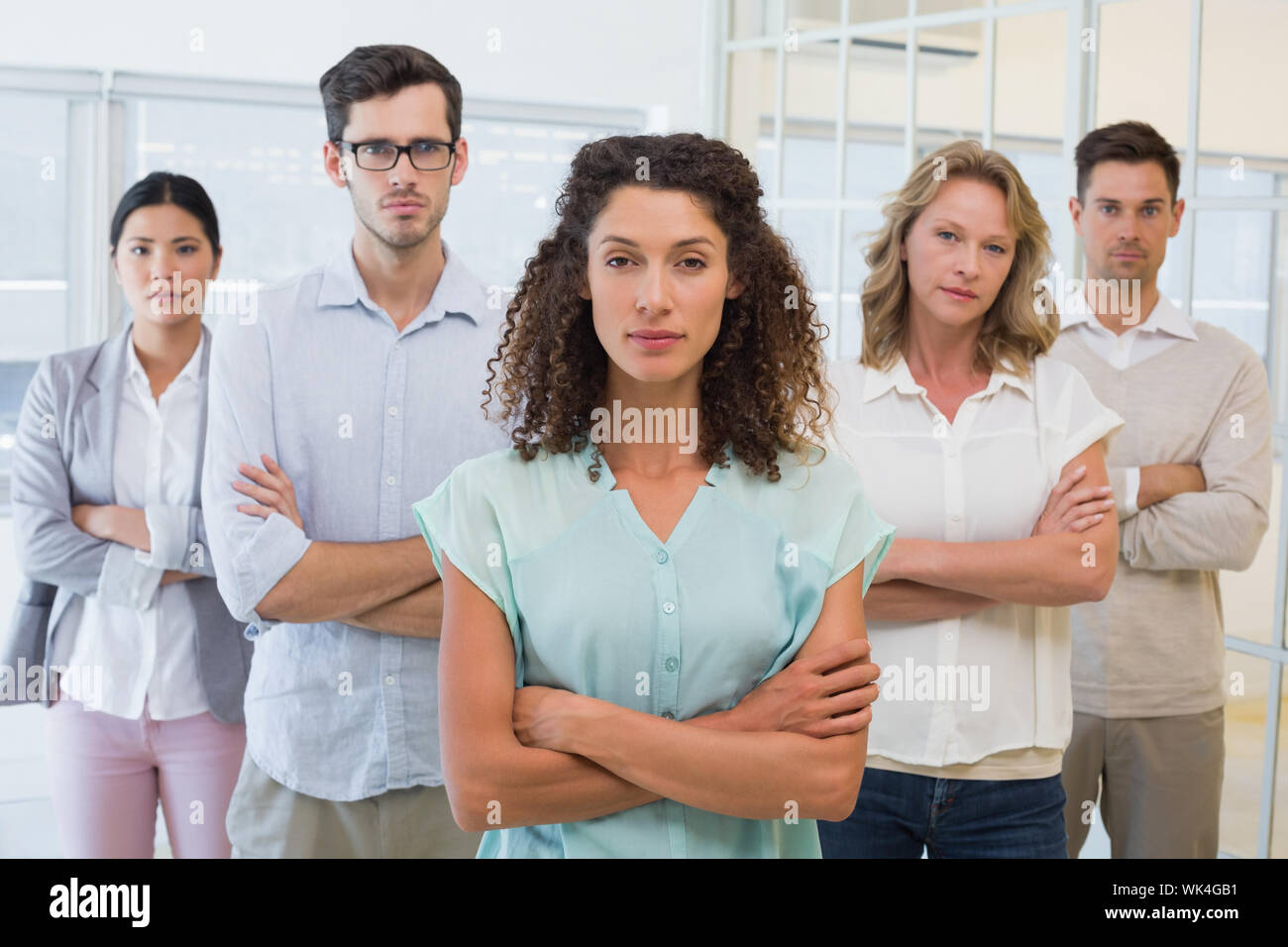 Casual business team frowning at camera with arms crossed in the office ...