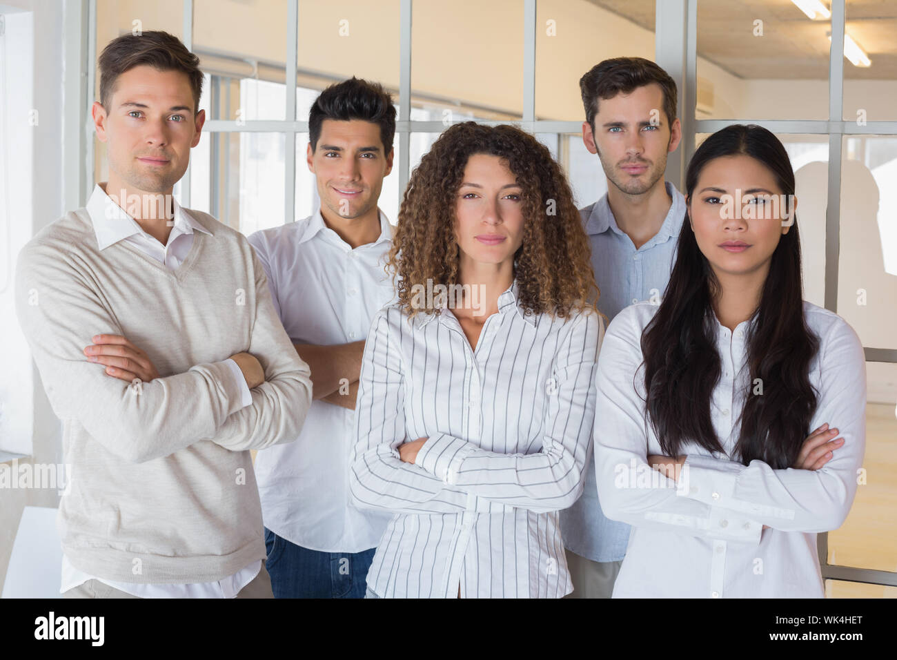 Casual business team looking at camera with arms crossed in the office ...