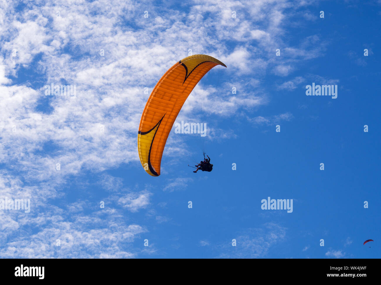Low Angle View Of People Paragliding Against Blue Sky Stock Photo