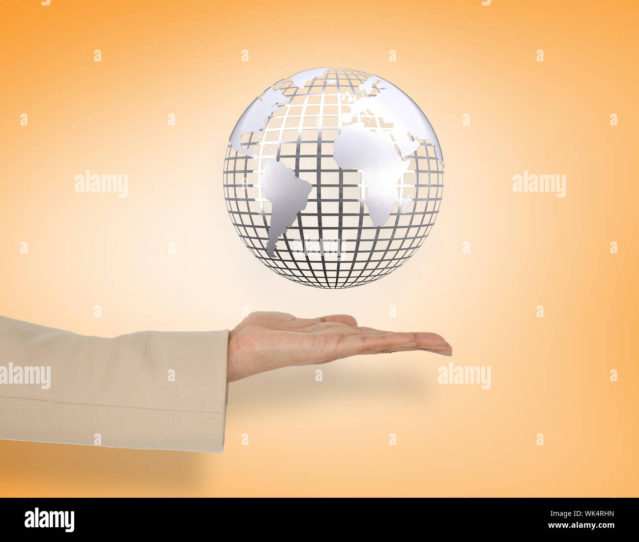 Female hand presenting silver globe against orange vignette Stock Photo