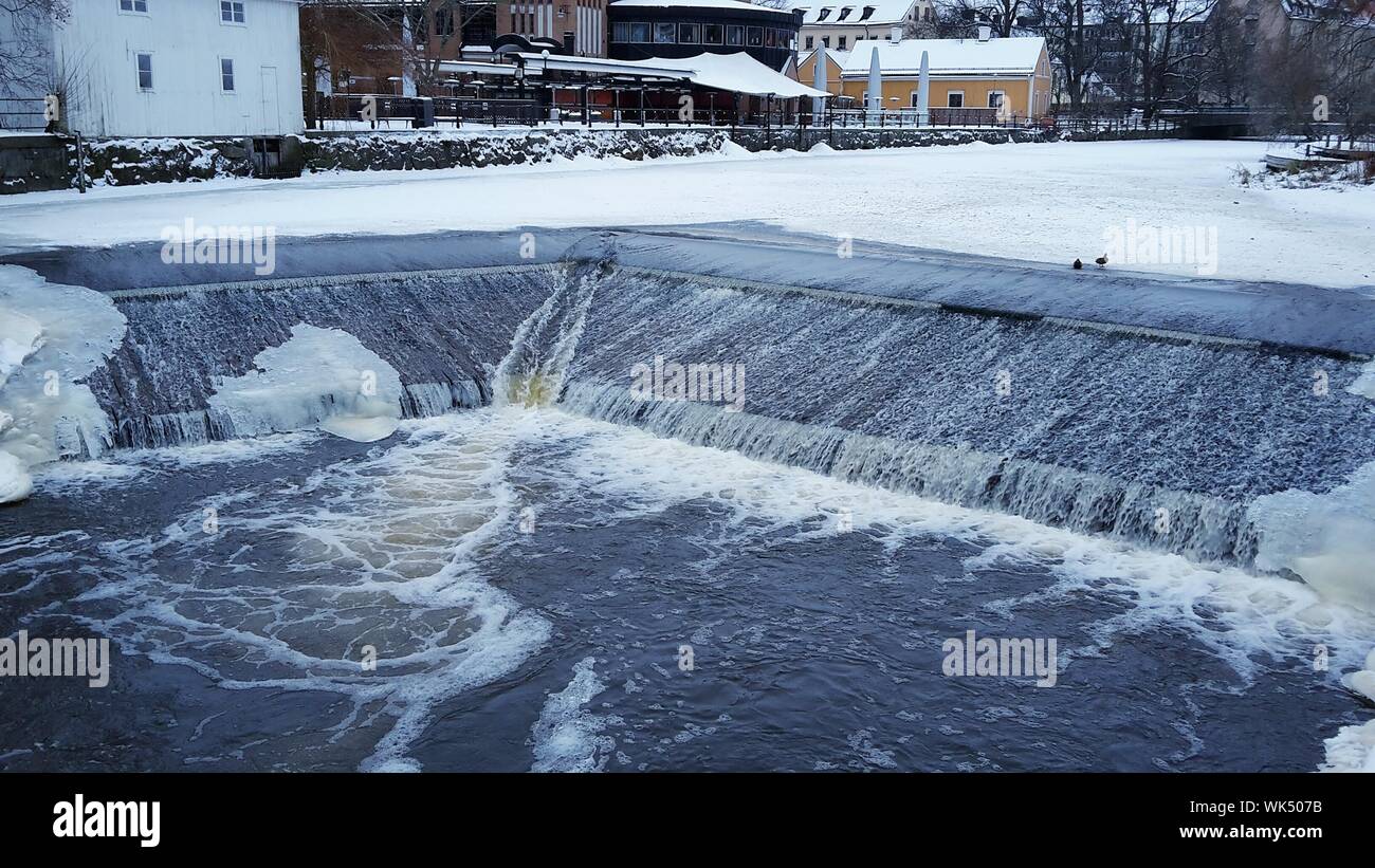 Flowing Water From Frozen River In City Stock Photo