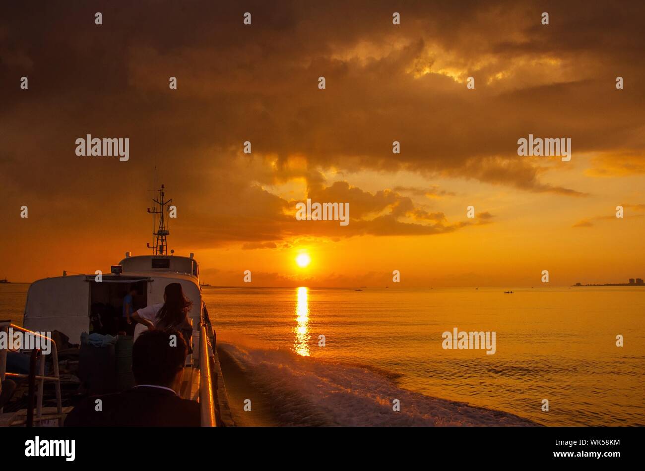 Tourists In Boat On Sea During Sunset Stock Photo