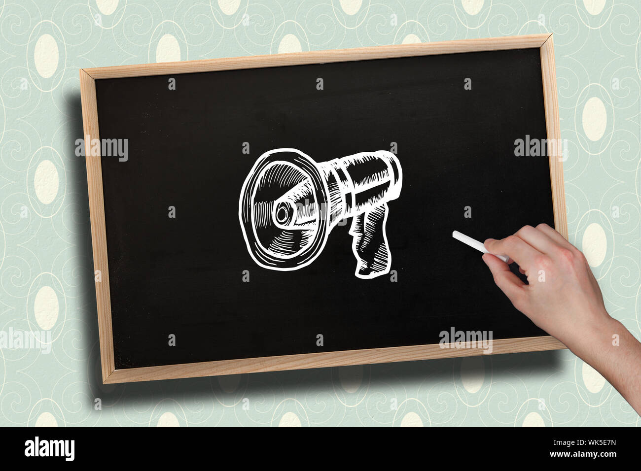 Composite image of hand drawing megaphone with chalk on chalkboard with ...