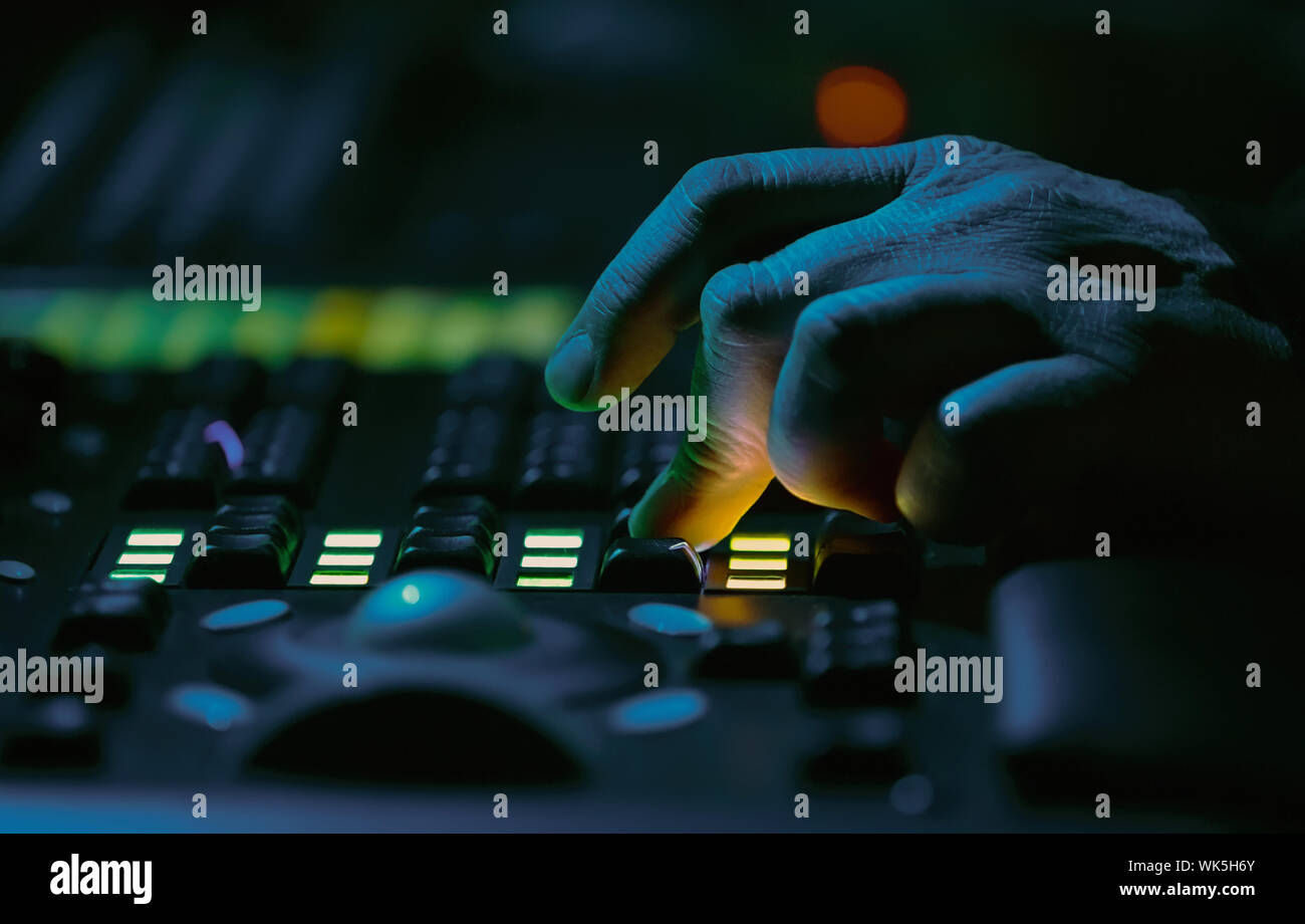 Sound technician works on audio mixer panel at rock concert in