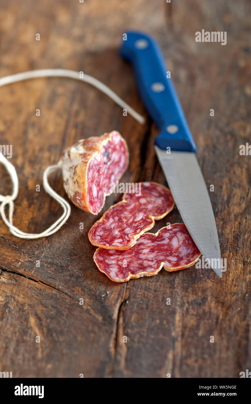 slicing italian salame pressato pressed over old wood table Stock Photo