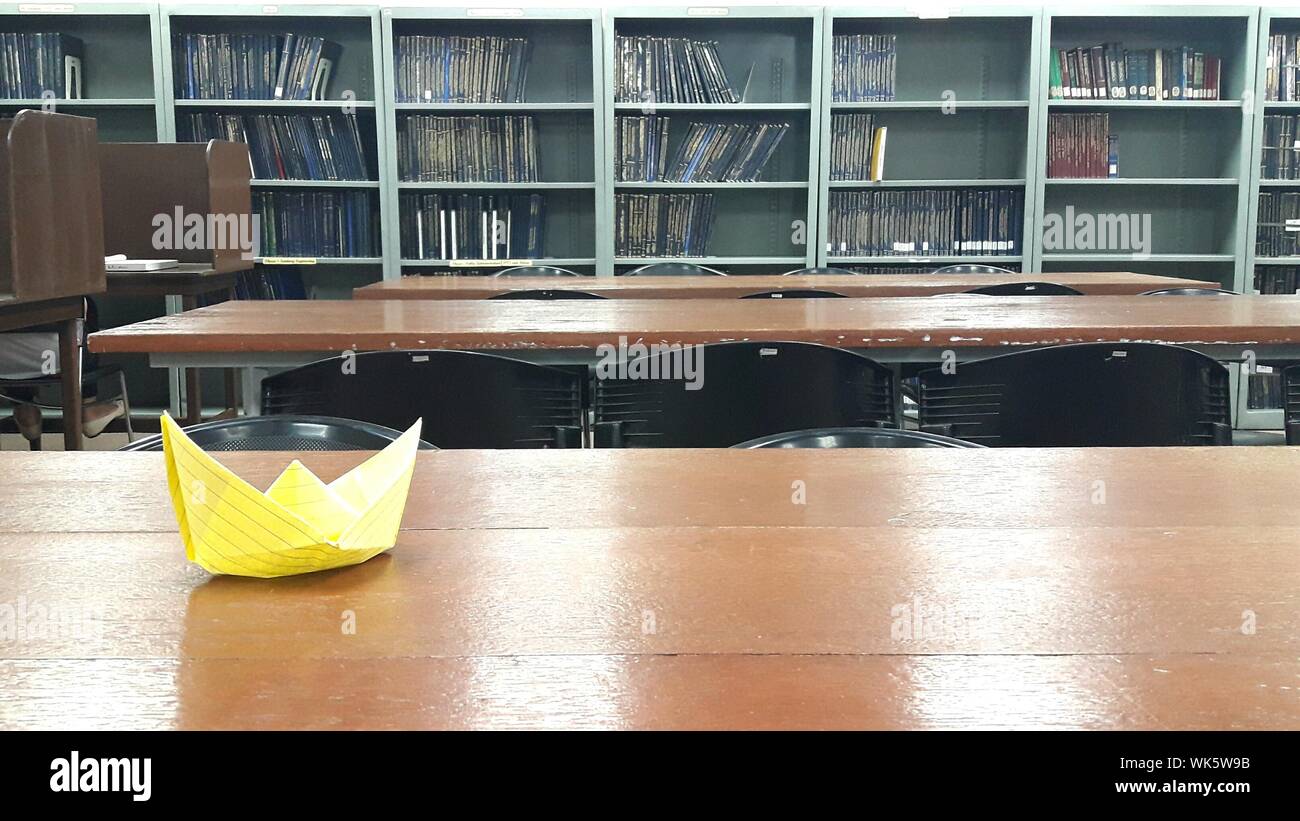 Close Up Of Paper Boat On Wooden Table In Library Stock Photo