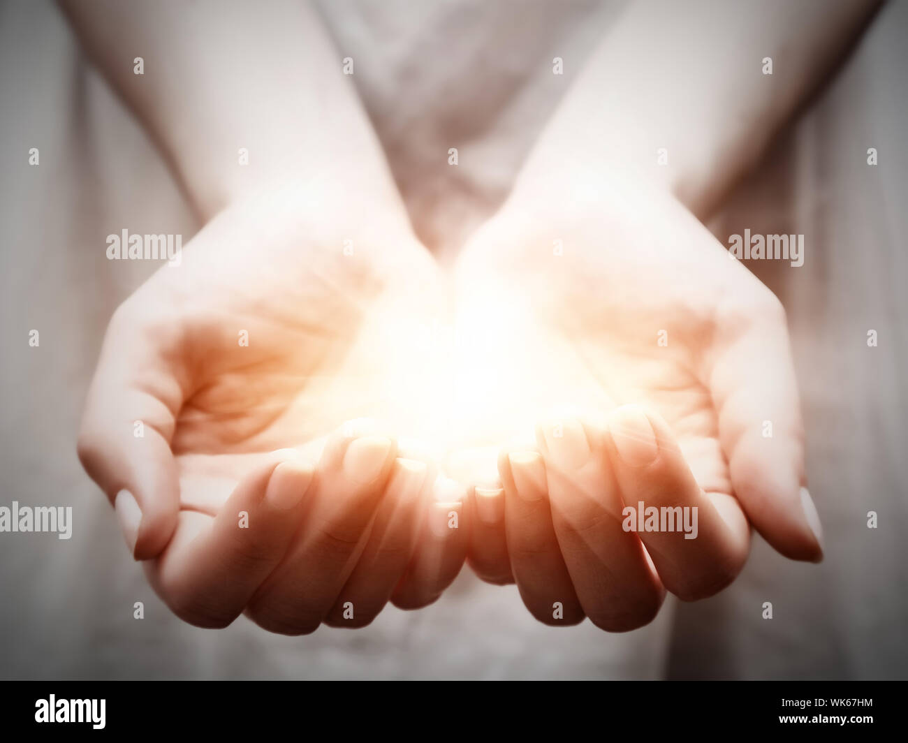 The light in young woman hands in cupped shape. Concepts of sharing, giving, offering, taking care, protection Stock Photo