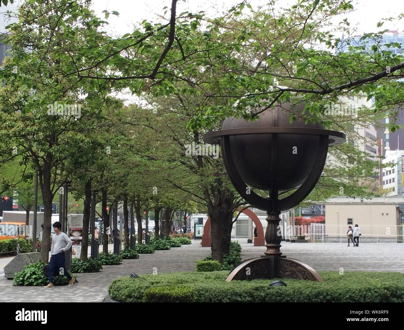 Globe Sculpture In Tree-lined City Street Stock Photo
