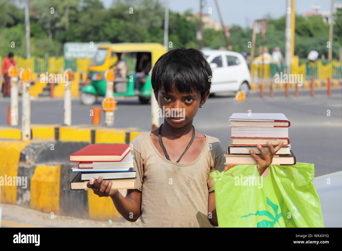 Boy selling stack of books on the road, New Delhi, India Stock Photo