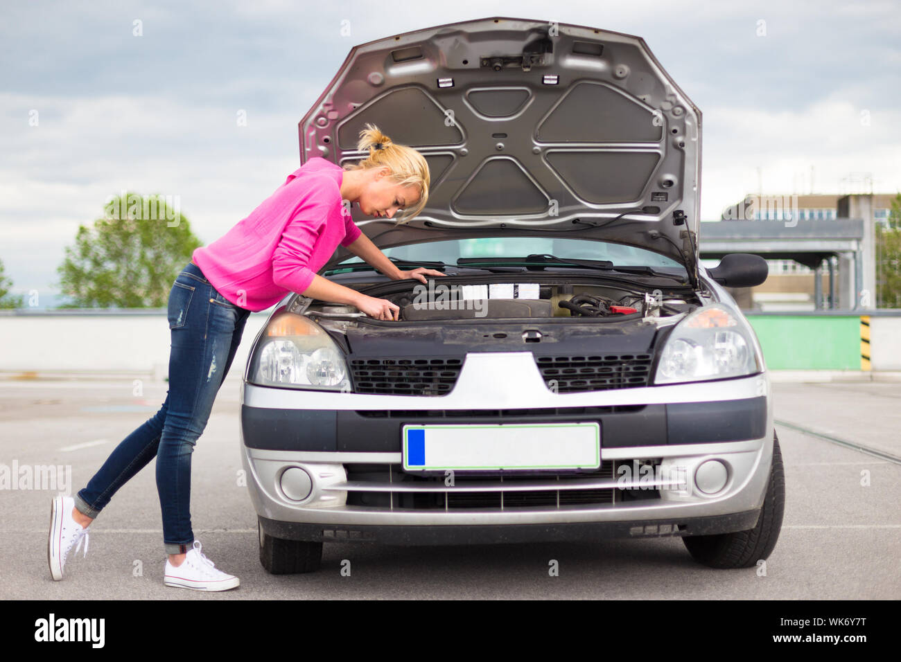 Woman inspecting broken car engine. Stock Photo