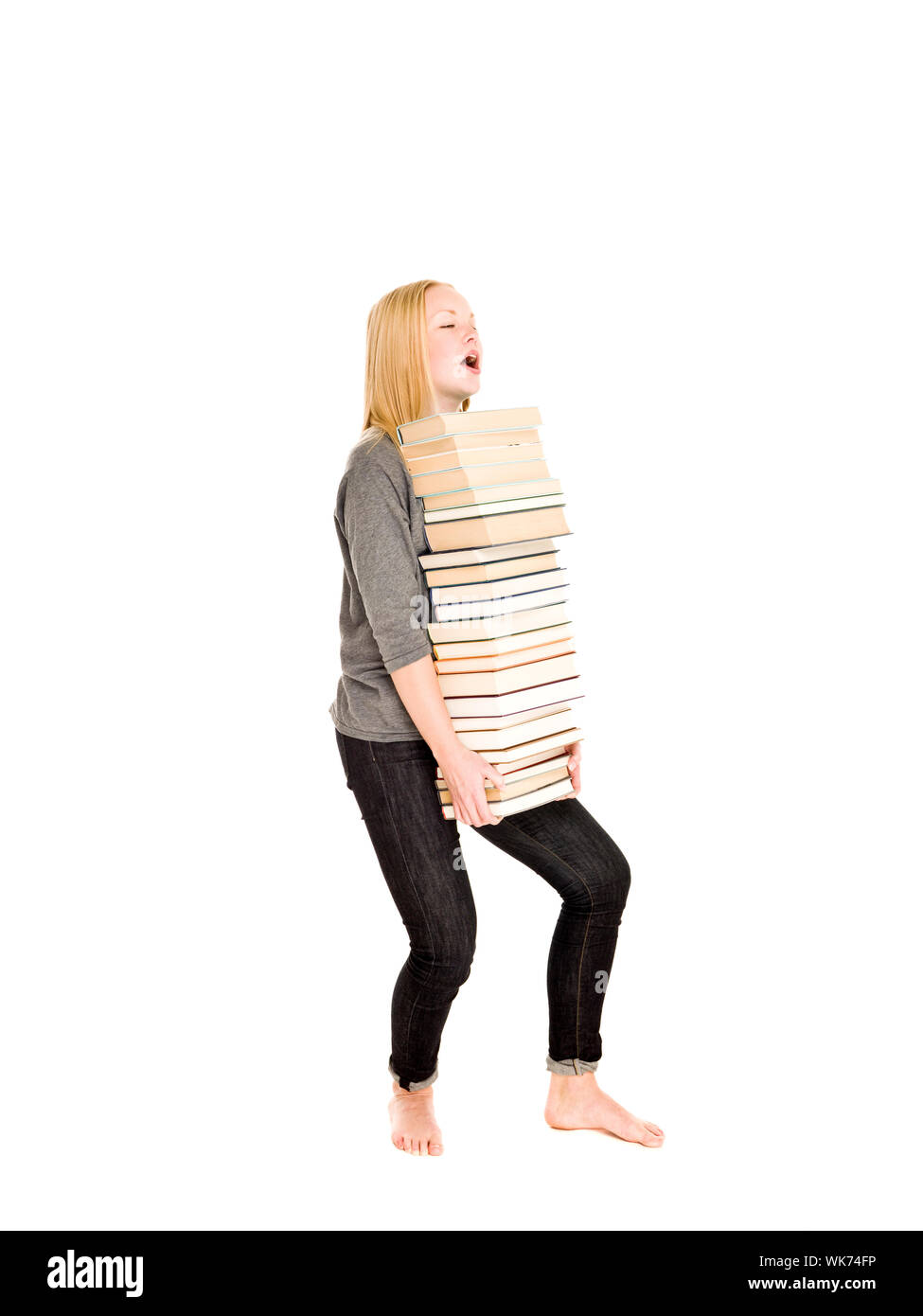 Young girl carrying a heavy pile of books isolated on white background ...