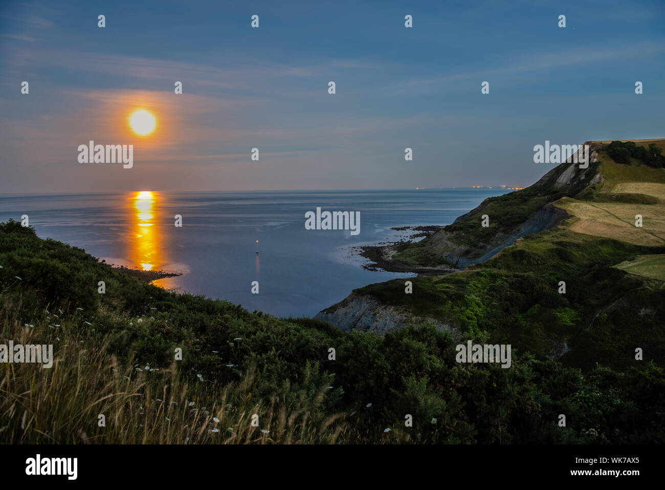 View of the moon setting at Chapman's pool from the cliff top. Stock Photo