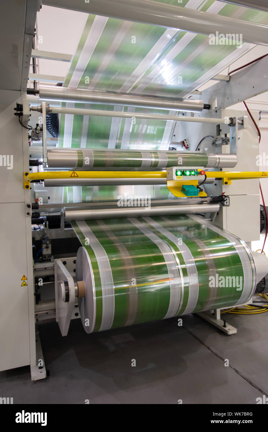 Plastic film processor with fast-moving green printed film unwinding and going overhead (Portrait) Stock Photo