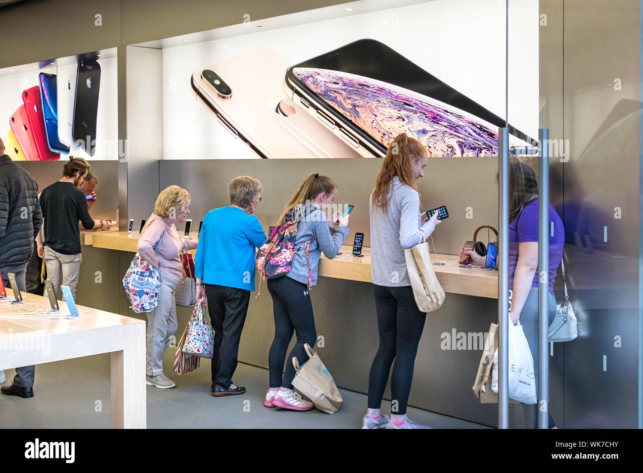 Belfast, Northern Ireland, UK - July 30, 2019: Senior and young women testing and looking iPhones inside an Apple Store in Belfast, Northern Ireland, Stock Photo