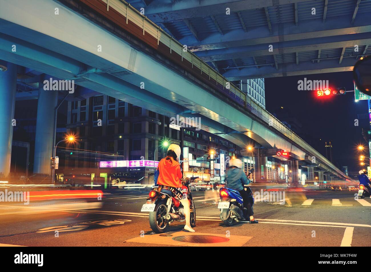Rear View Of People Riding Motor Vehicles On Road At Night Stock Photo