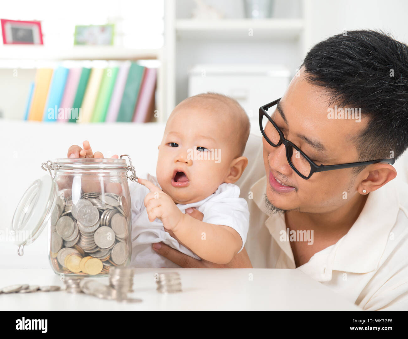 Asian family lifestyle at home. Father and child saving coins to money jar, financial planning ...