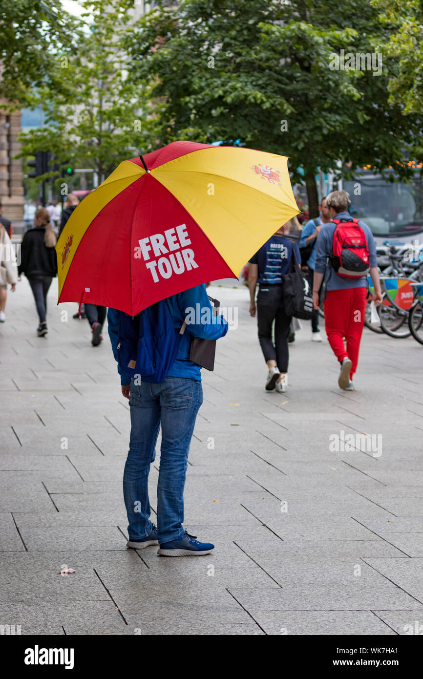 Belfast, Northern Ireland, UK - July 30, 2019: A man standing at the city hall holding an umbrella promoting a free tour offered by the Belfast Munici Stock Photo