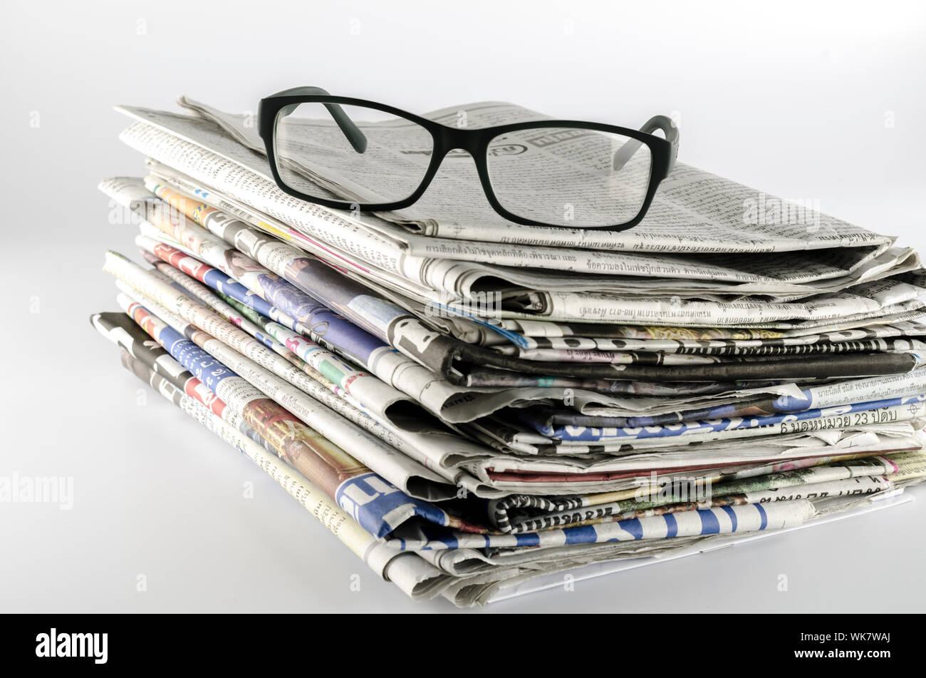 stack of newspaper with glasses on a white background Stock Photo - Alamy